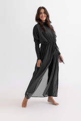 Woman wearing a black dress with sheer overlay on a white background